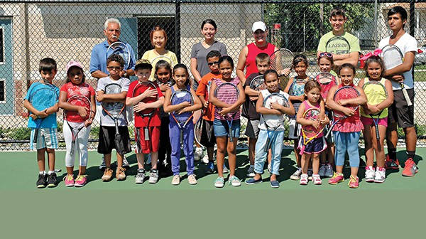 Kids holding tennis racquets.