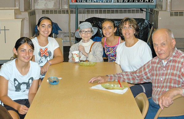 Marie in one of her famous hats is surrounded by her 3 Granddaughters, her Daughter-in-law, Stephanie and Marie’s Husband of 63 yrs, Andrew at a Ice Cream Social, Holy Spirit Church. *File Photo by Paul Wang