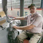“Capt” Bill McKelvy, Director and Site committee chairman, sits at the controls of his General Electric 45 ton 300 horsepower locomotive.