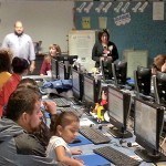 Parents and their children have a hands on experience inside the MyOn Classroom using computers to access information.